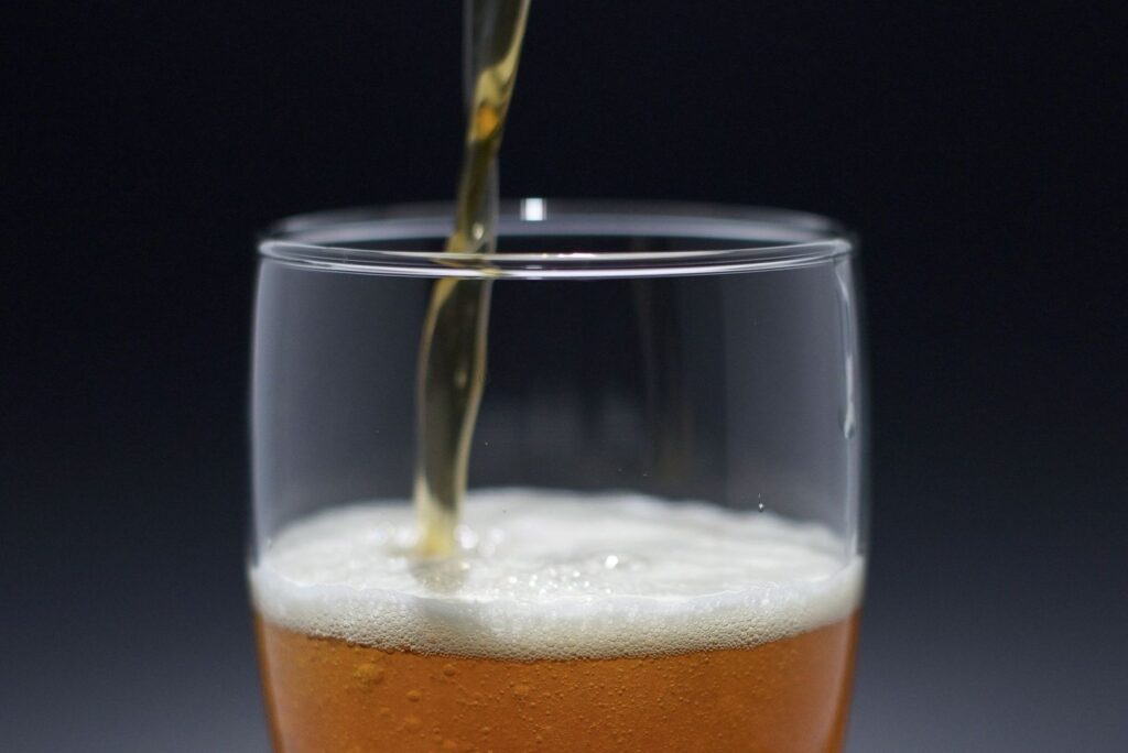 Öl hälls i ett glas och bildar en tät, bubblig skumkrona